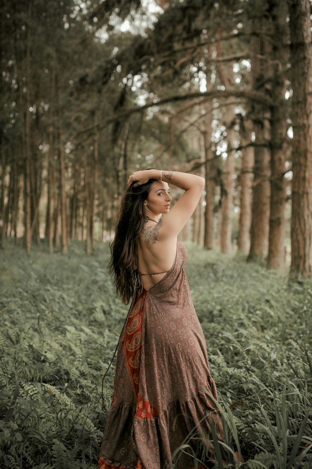 a woman in a dress standing in a forest