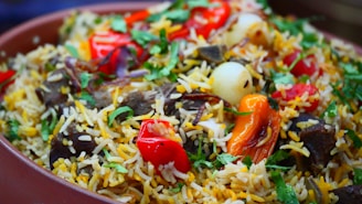 A vibrant dish filled with long-grain rice, herbs, and spices. The rice is garnished with fresh cilantro, red and yellow bell peppers, onions, and pieces of meat, creating a colorful and appetizing presentation.