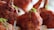 Close-up view of crispy, fried pieces of chicken with a rich, reddish-brown coating, garnished with fresh green herbs.