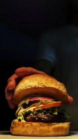 a person holding a large hamburger in their hand