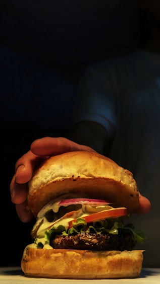 a person holding a large hamburger in their hand