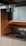A modern kitchen sink area with wooden cabinetry and a sleek metal faucet. The minimalist design includes overhead shelving with warm ambient lighting underneath.