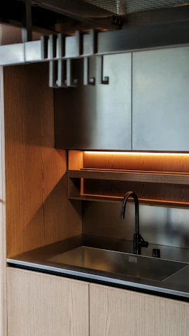 A sleek 3 BHK apartment kitchen with warm wooden cabinets and smart storage solutions.