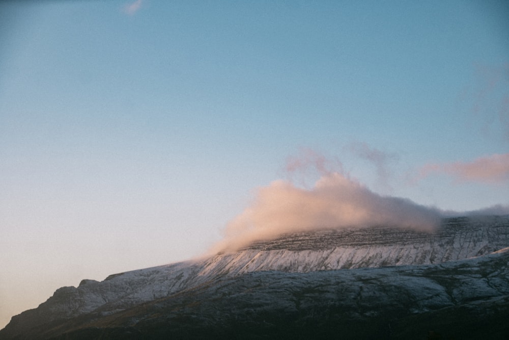 a snow covered mountain with a cloud in the sky