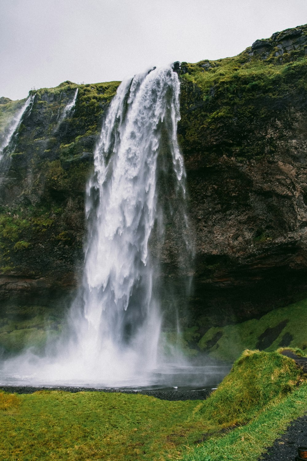 a large waterfall is in the middle of a grassy area