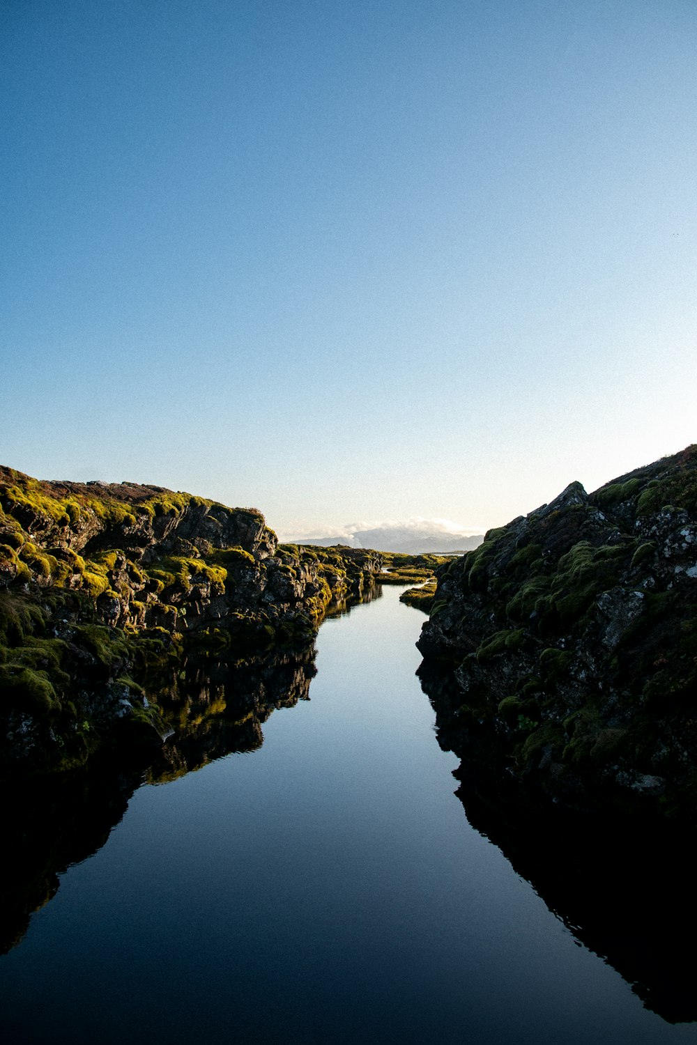 uno specchio d'acqua circondato da una collina verde e rigogliosa