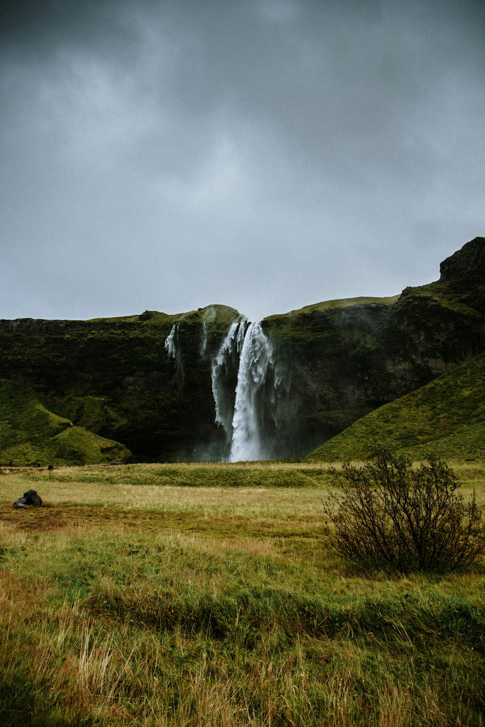 a large waterfall in the middle of a grassy field