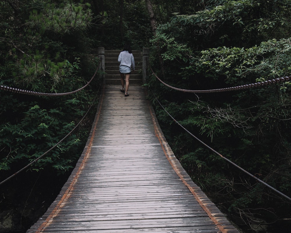 a person walking across a bridge in the woods