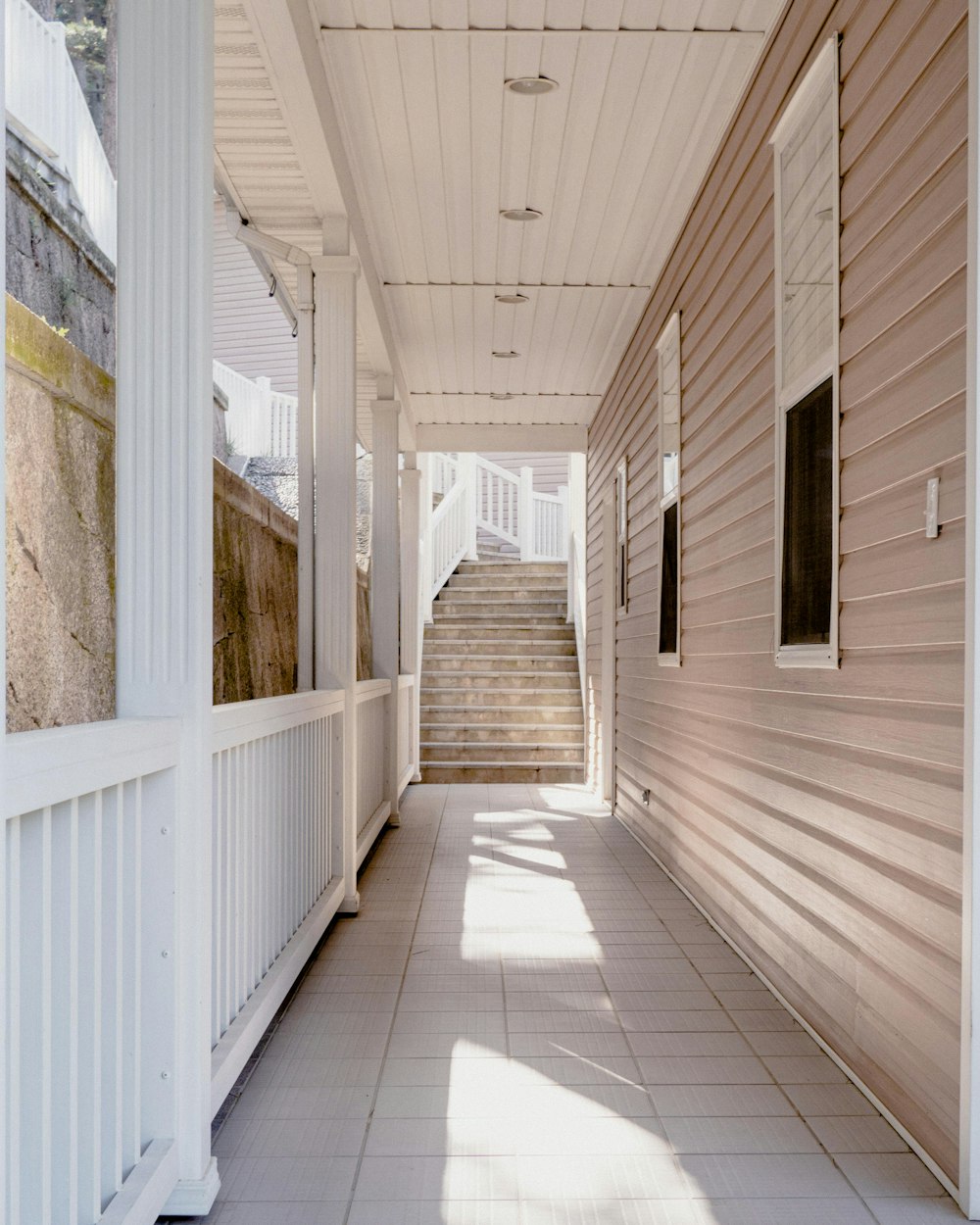 a long hallway with a white railing and a set of stairs