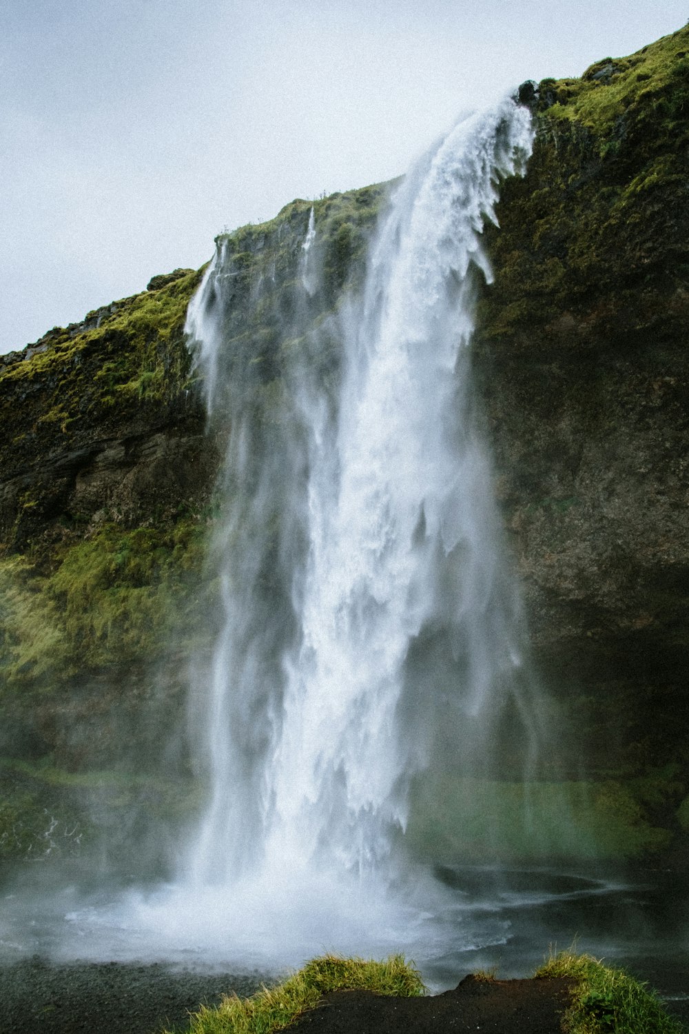 a large waterfall with a man standing in front of it