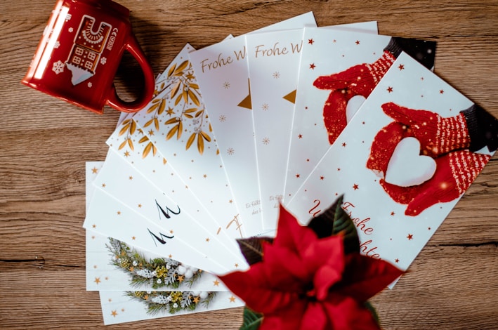 A cozy scene showing a variety of colorful Christmas cards spread out on a wooden table.