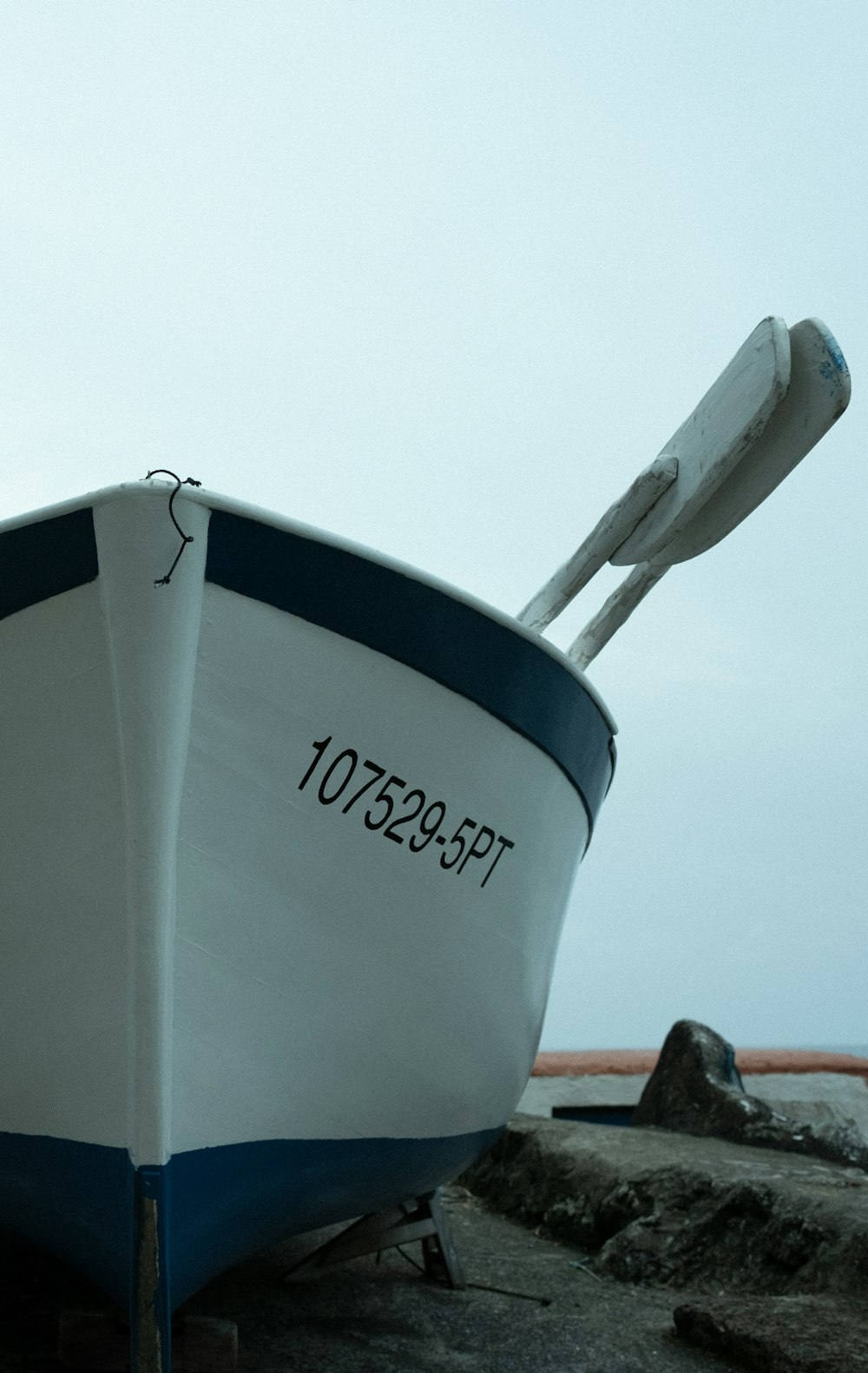 a white and blue boat sitting on top of a beach
