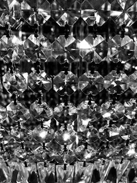 A detailed close-up of a pattern of sparkling, geometric crystal-like beads arranged in rows, reflecting and refracting light.