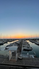 A peaceful marina dock at sunset with boats gently bobbing on calm waters.