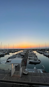 A peaceful marina dock at sunset with boats gently bobbing on calm waters.
