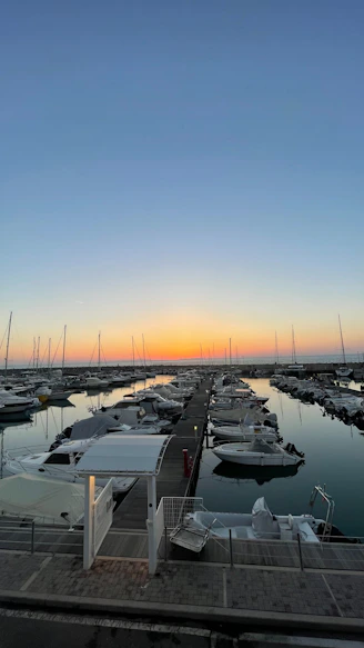 A cozy marina at sunset with boats gently rocking on calm water.