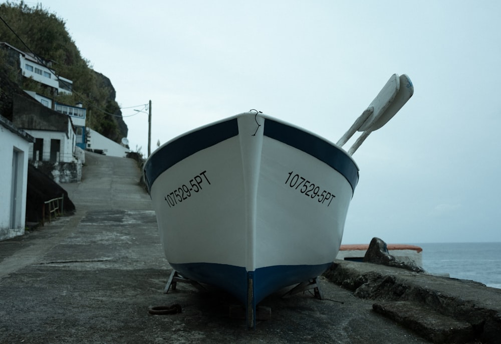 a boat sitting on the side of a road next to the ocean