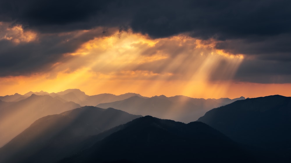 the sun is shining through the clouds over the mountains