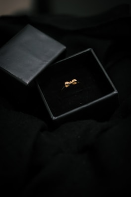 Close-up of a sleek black box with silver delini logo, slightly open to reveal a minimalist ring inside.