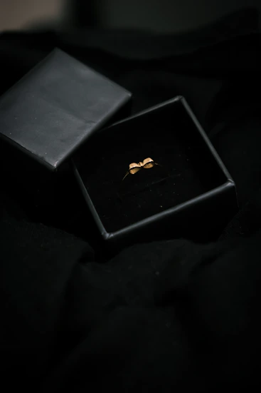 A sleek black and gold jewelry box with delicate handmade earrings inside, softly lit to highlight the craftsmanship.