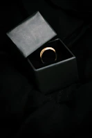 Minimalist gold ring with a smooth finish resting on soft black velvet.