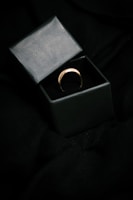 Close-up of a sleek gold ring with a minimalist design on a dark velvet background.