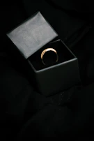 Minimalist photo of a champagne gold ring on a black velvet cushion.