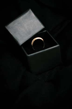 A minimalist black jewelry box with silver accents, softly lit against a dark background.