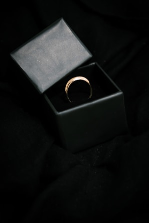 Close-up of a sleek gold ring with a minimalist design on a dark velvet background.