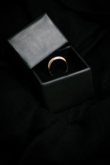 Minimalist 10k gold ring with a smooth finish resting on a black silk cloth