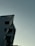 A modern building with a sharp, angular design is partially visible, with the logo 'CMAX' on the side. The background consists of a smooth, cloudy sky with dim lighting, suggesting evening or early morning.