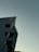 A modern building with a sharp, angular design is partially visible, with the logo 'CMAX' on the side. The background consists of a smooth, cloudy sky with dim lighting, suggesting evening or early morning.