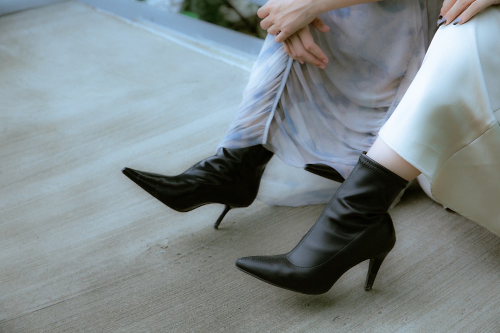 a woman sitting on the ground wearing high heel boots