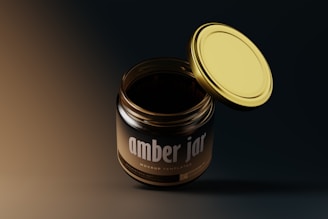 A glass jar with a dark amber color and a metallic gold lid, slightly open. The label reads 'amber jar' mockup template. The background is a gradient of dark to medium tones, providing a modern and minimalist aesthetic.