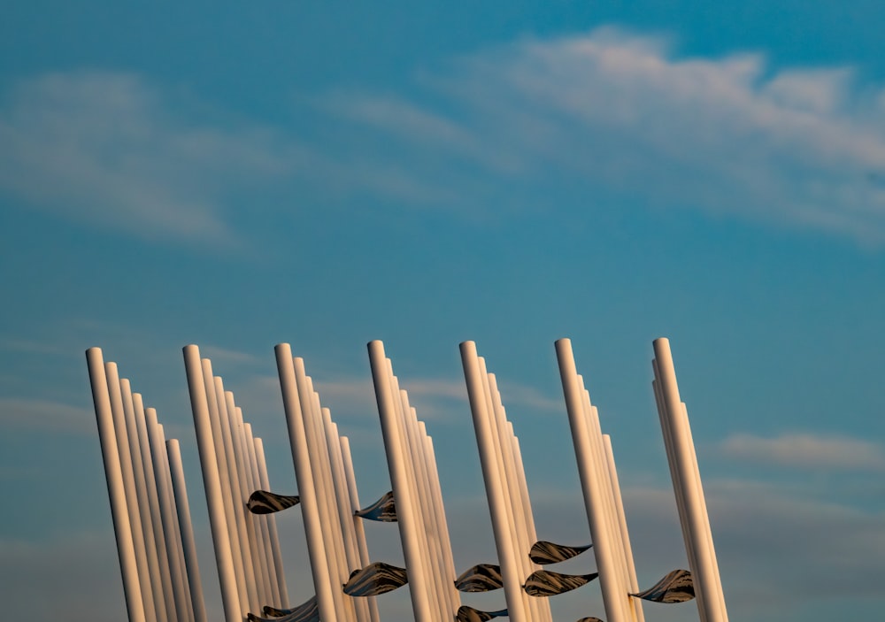a row of tall white poles with birds flying over them