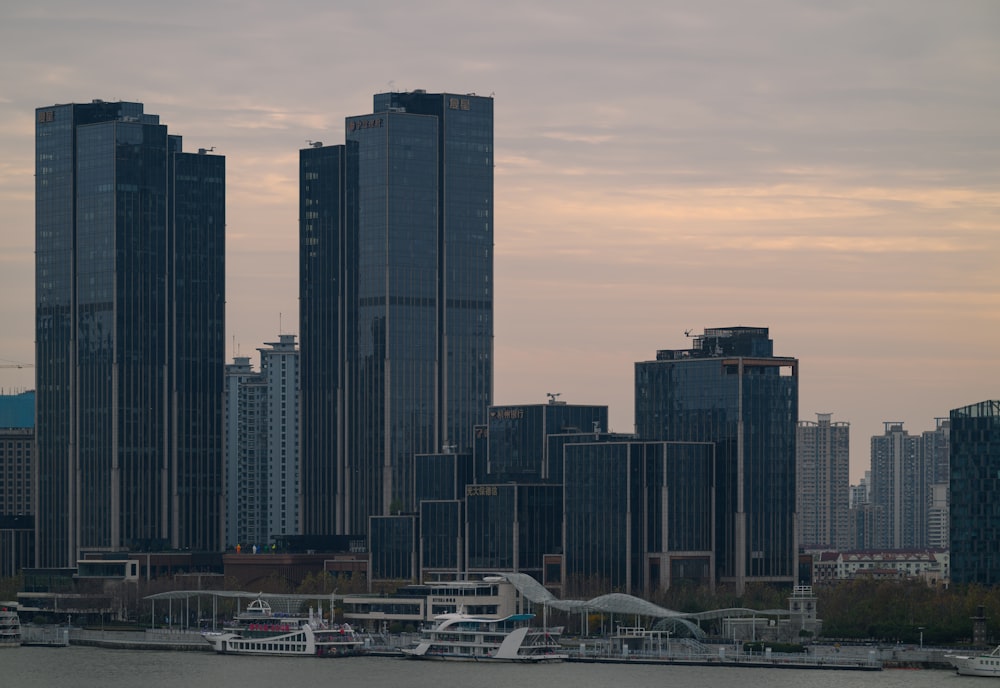 a city skyline with tall buildings and boats in the water