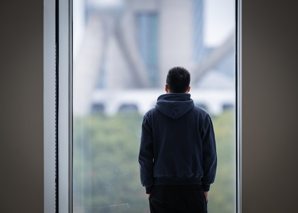 a man standing in front of a window looking out