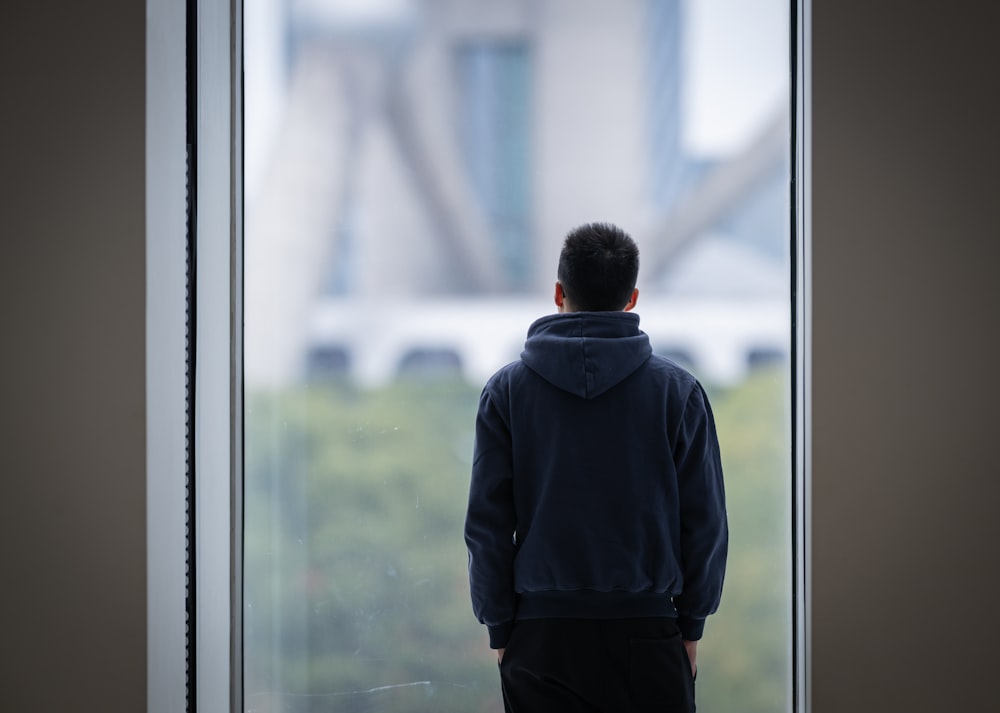 un hombre parado frente a una ventana mirando hacia afuera