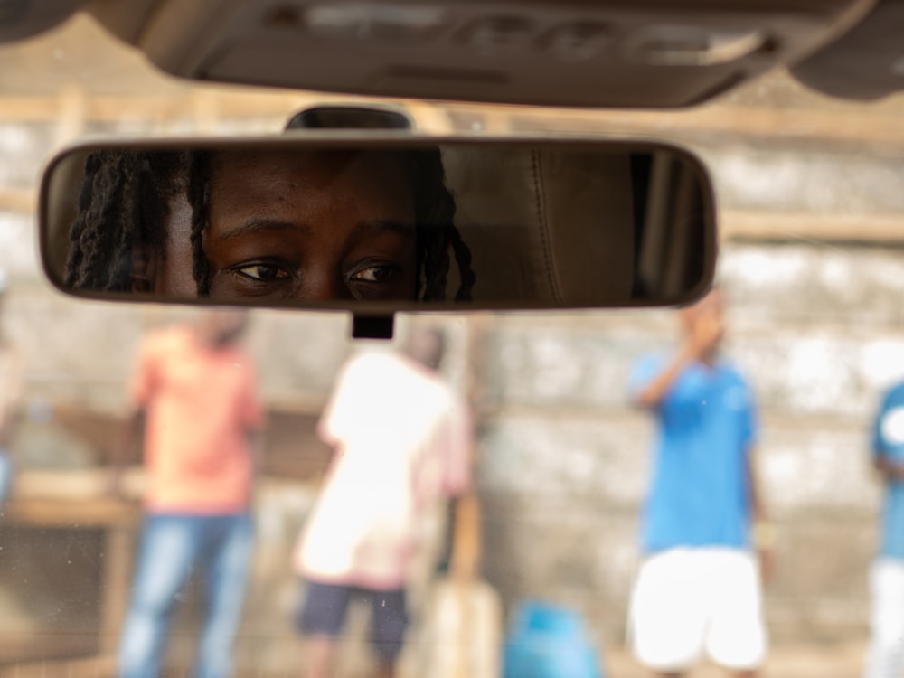 a woman is reflected in the rear view mirror of a car