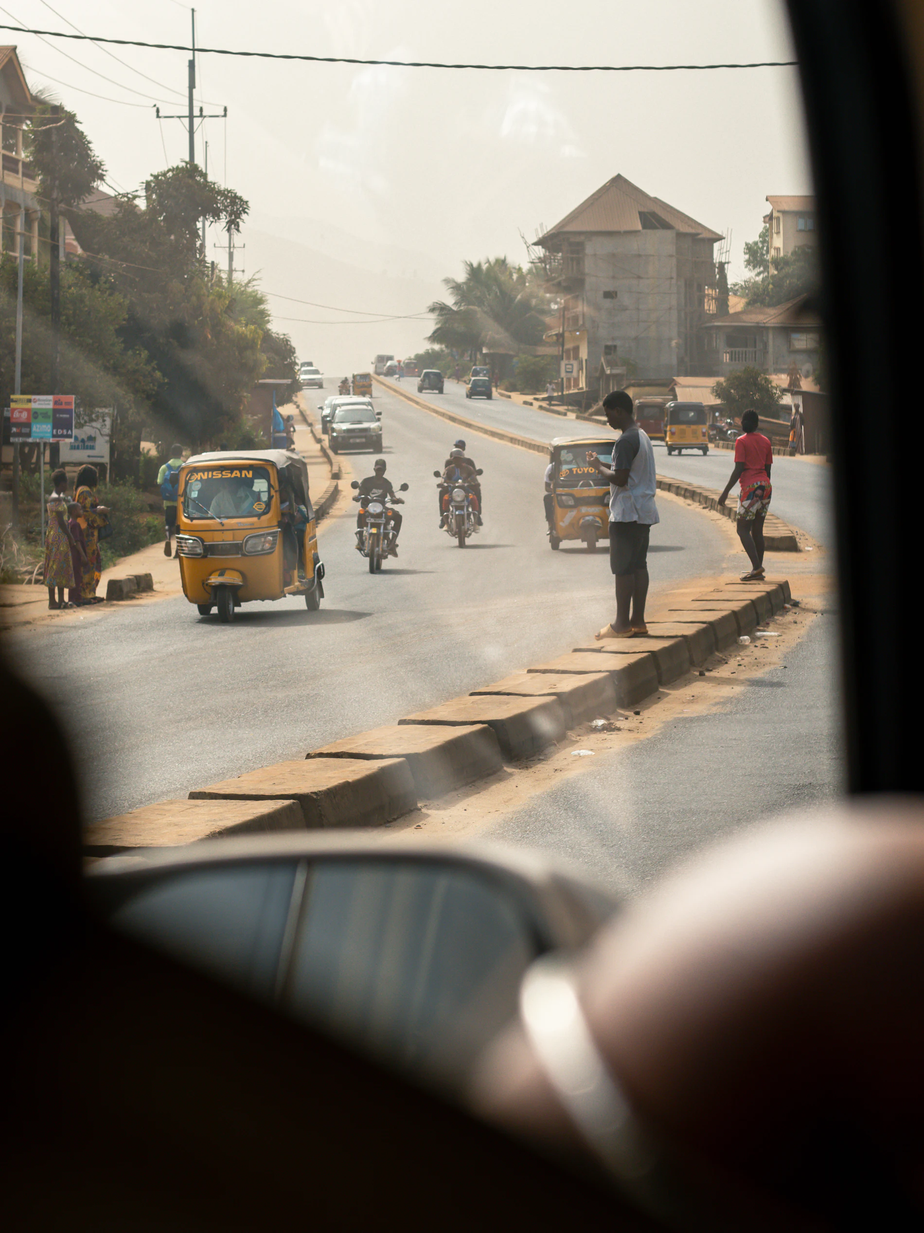 Rue ouest-africaine, plusieurs conducteurs de deux-roues en circulation.