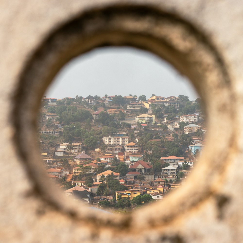 a view of a city through a hole in a stone wall