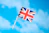 a small british flag flying in the blue sky