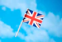 a small british flag flying in the blue sky