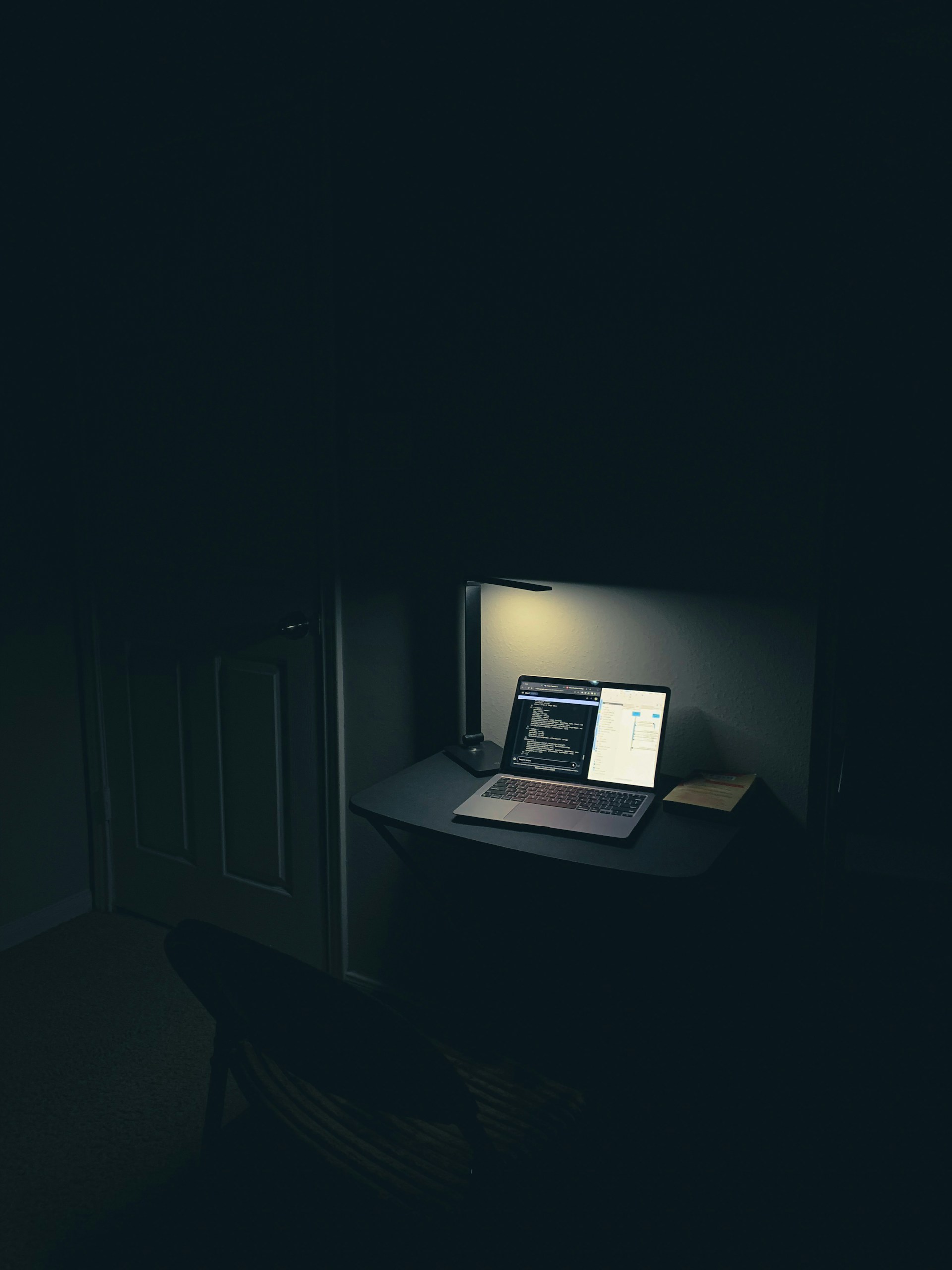 a laptop computer sitting on top of a desk in a dark room