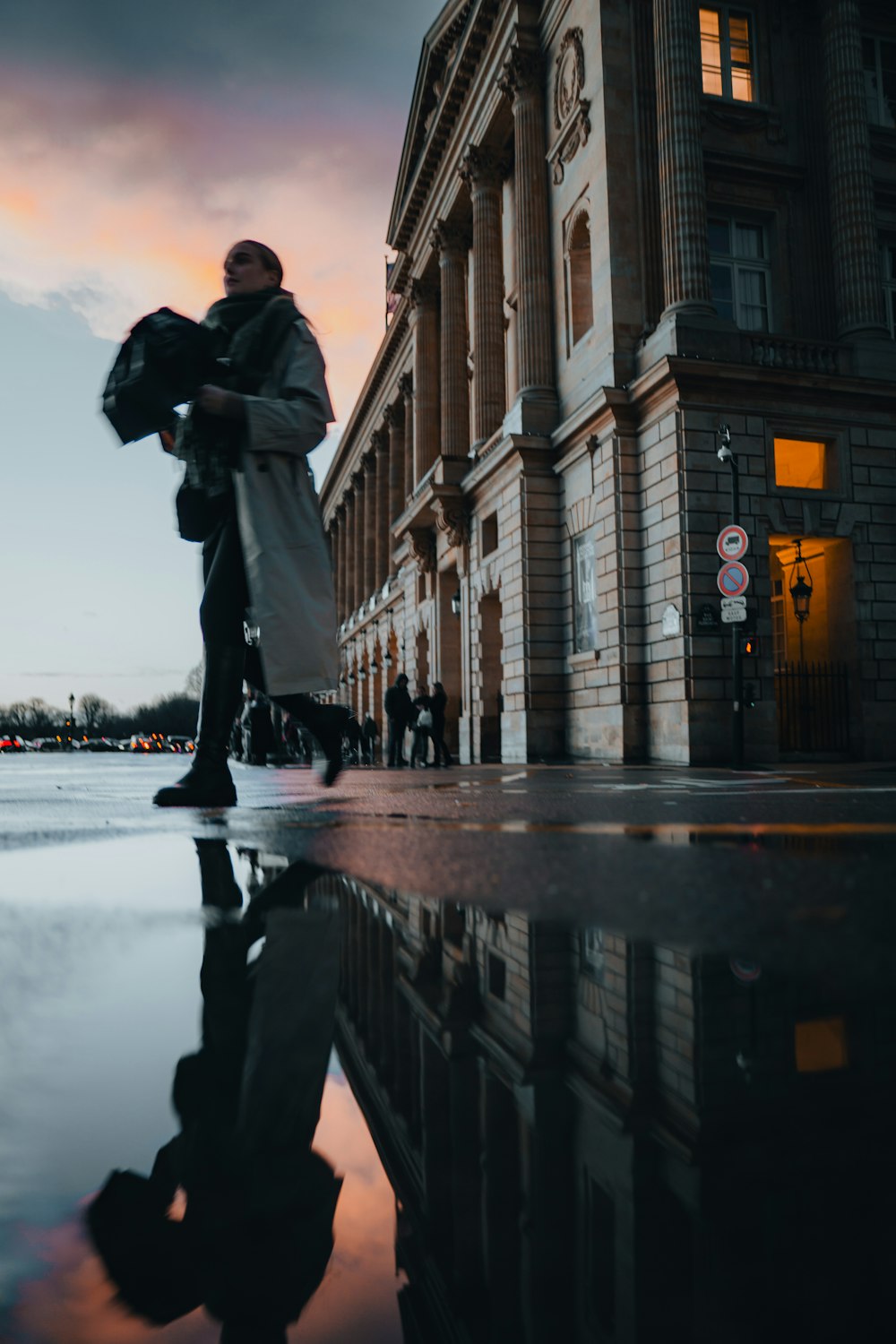 a man walking down a street next to a tall building