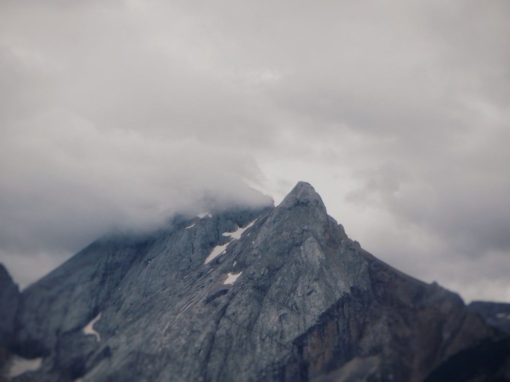 a very tall mountain covered in snow under a cloudy sky