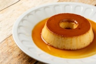 A dessert plate featuring a slice of creamy flan topped with caramel sauce.