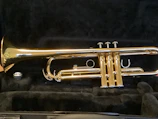 Hands carefully restoring an old trumpet, surrounded by tools and polish.