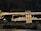 A shiny brass trumpet is placed in a black padded case. The instrument's bell, valves, and tubing are visible with the brass reflecting light, indicating that it is well-polished.
