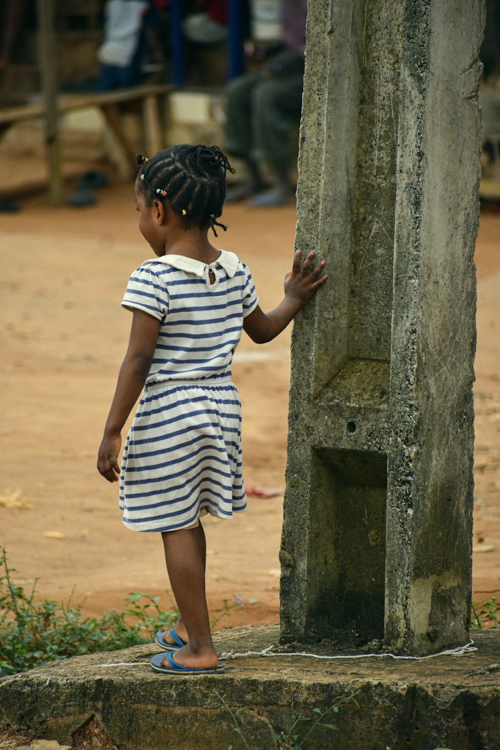 a little girl standing next to a wooden pole